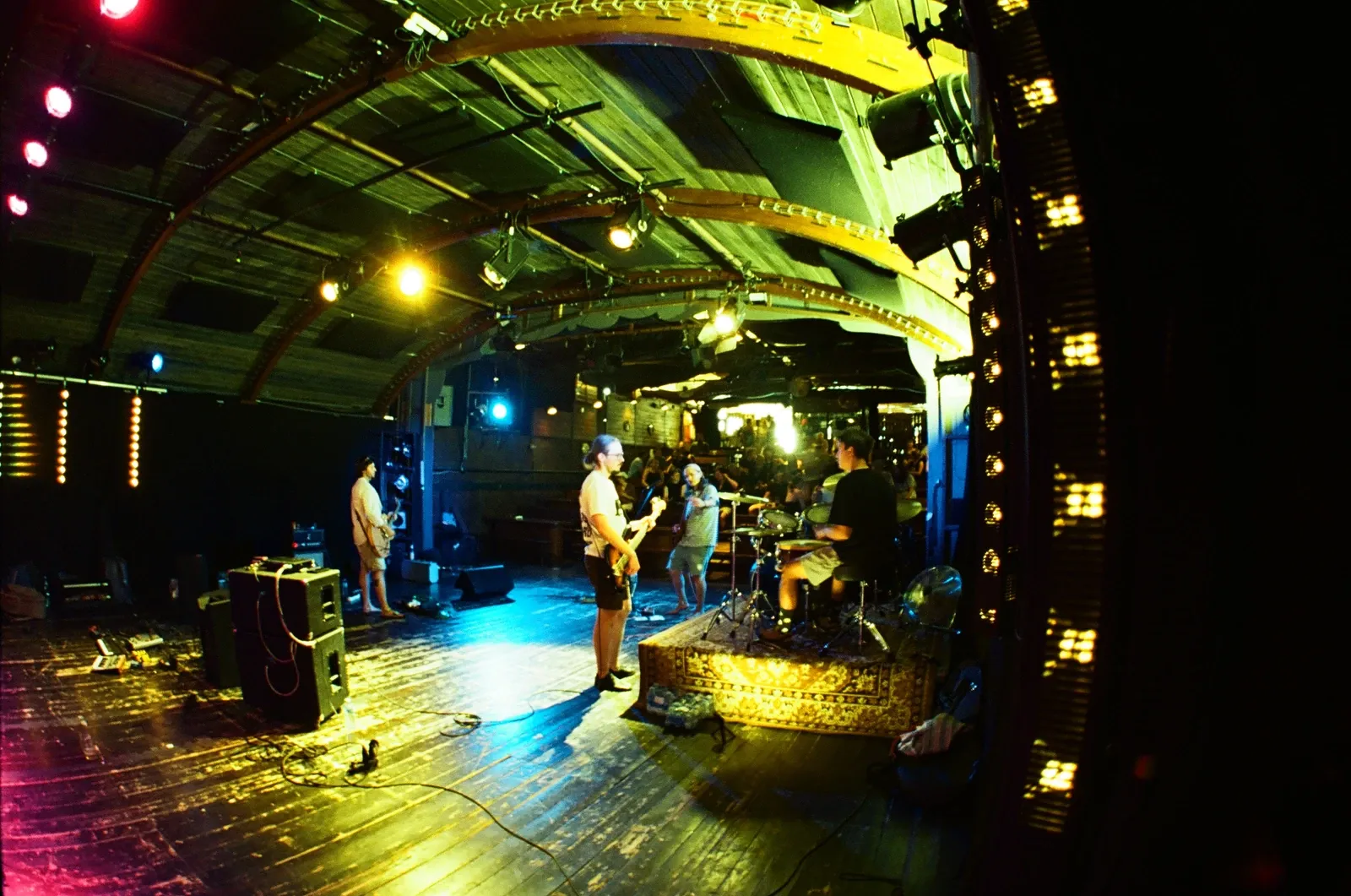 Chroustones from behind the guitarist: drummer and bassist on the arched wooden stage