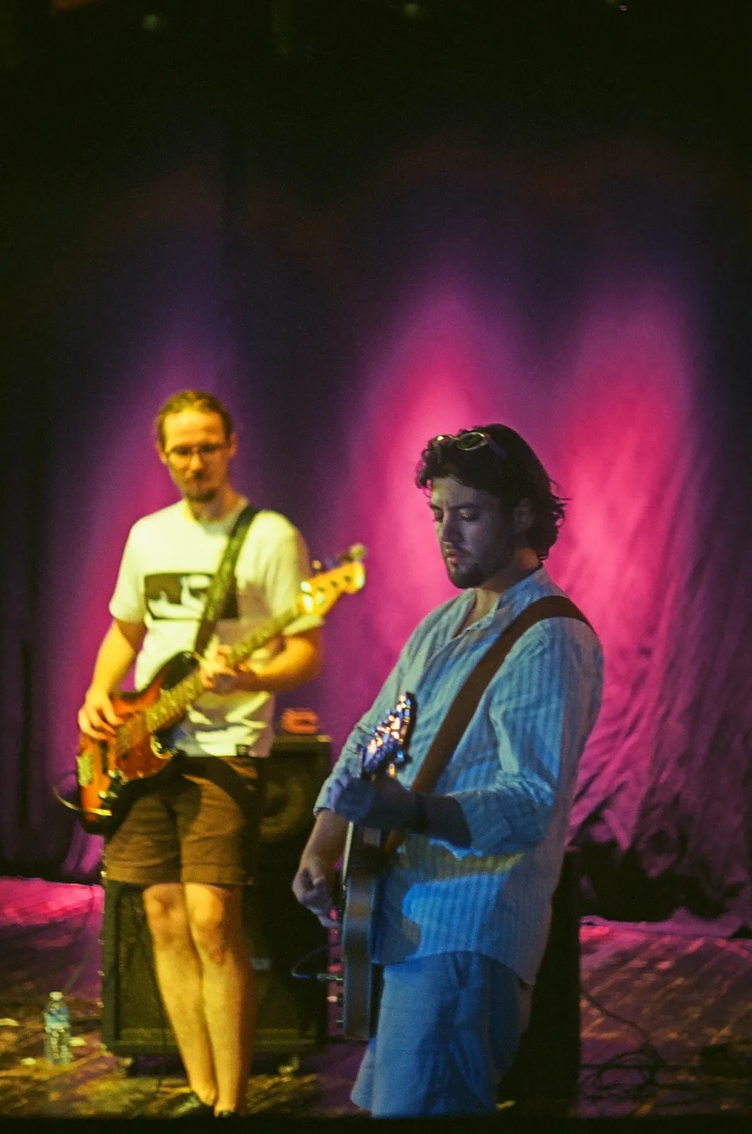 Guitarist and bassist of Chroustones bathed in pink stage light at Loď Tajemství