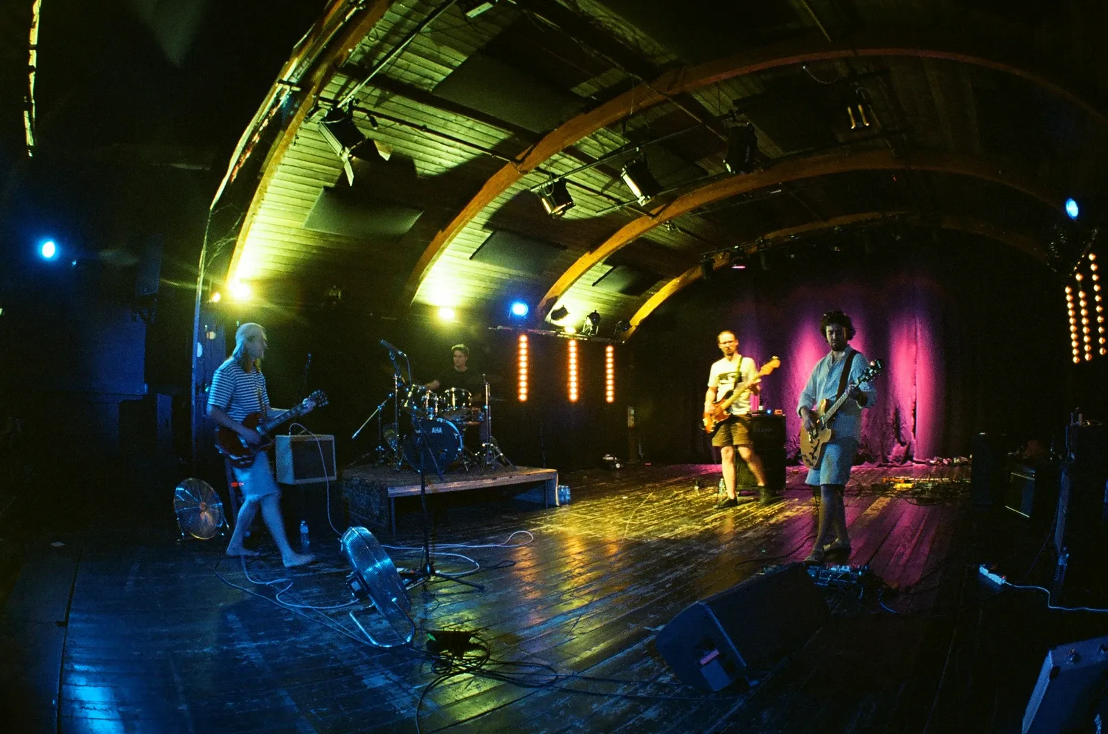 Chroustones playing live on the boat stage at Loď Tajemství, Prague, under blue, yellow and pink stage lights